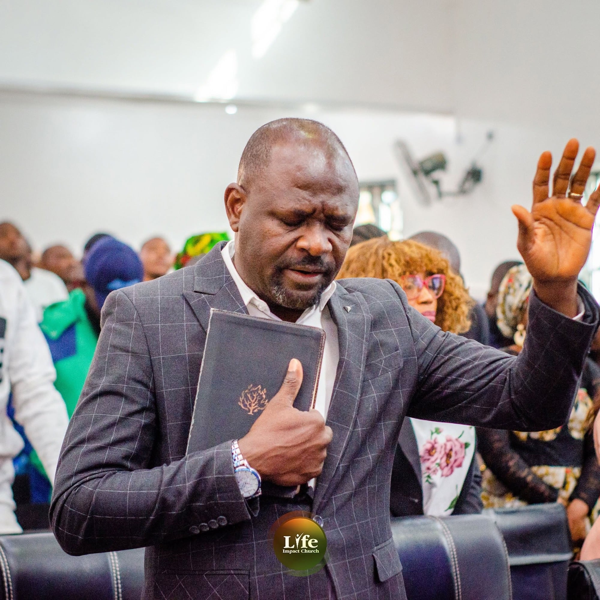 A minister praying with his Bible held to his heart and a hand raised